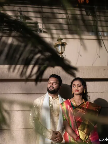 An artistic shot of the couple through palm leaves, adding a layer of intimacy and creative framing.