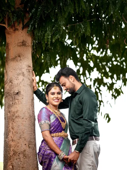 A sweet moment between the couple under a tree, capturing a natural and candid interaction.