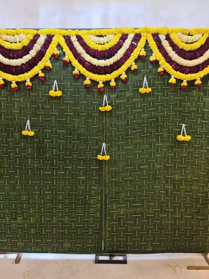 A simple and traditional backdrop created from woven coconut leaves (thoranam) and adorned with marigold and tuberose flowers. This is perfect for any pooja or small home function.