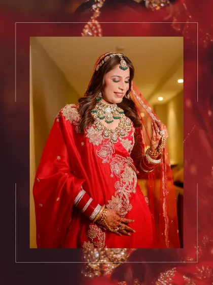 The bride adjusts her veil in a moment of quiet grace, her red and gold lehenga creating a stunning visual.
