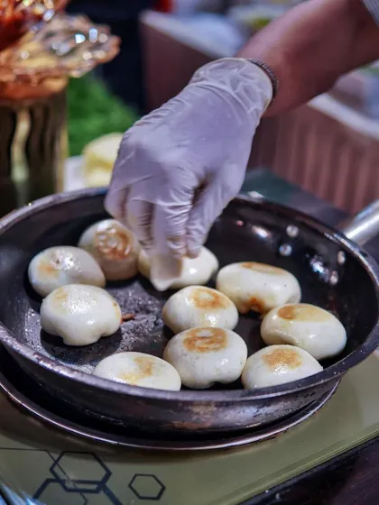 How 'bao' you? Here, my chef is pan-frying soft bao buns until they are perfectly golden brown, ready to be filled with deliciousness.