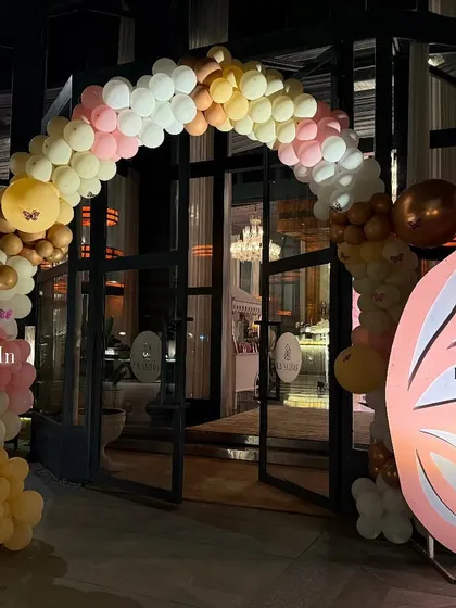 The balloon and butterfly wing entrance arch glowing against the evening sky, inviting guests into the celebration.