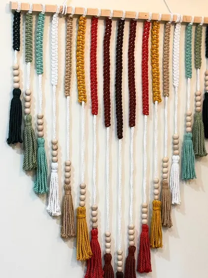 A close-up of the colorful wall hanging, showing the different colored tassels and wooden beads. Each one is handcrafted with care.