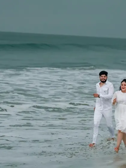 A wide shot of a couple running on the beach, conveying a sense of freedom and joy in their pre-wedding photos.
