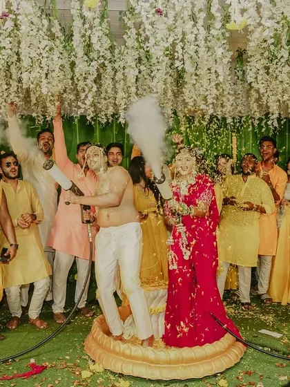 A wide shot of the Haldi celebration, capturing the couple, guests, and the festive decor.