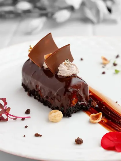 Our Ferrero Rocher Entremet is the epitome of chocolate and hazelnut indulgence. This image captures its glossy finish, creamy topping, and the promise of a rich, multi-layered experience.
