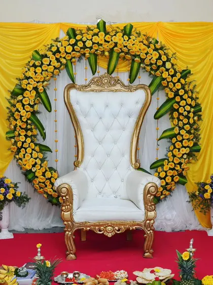 A bright and cheerful baby shower decoration using yellow roses. A large floral ring surrounds a white throne chair, creating a sunny and happy atmosphere for the mom-to-be.