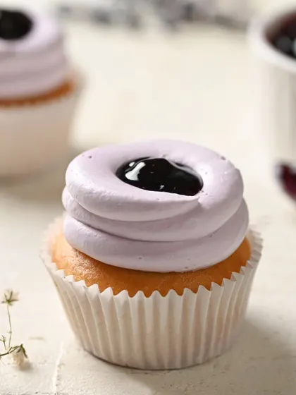 A perfect bite of our eggless blueberry cupcake. The vanilla base is topped with a light, blueberry-flavored frosting and a dollop of blueberry compote in the center.