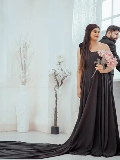 The couple posing in a brightly lit room, where the black trail gown creates a beautiful contrast.