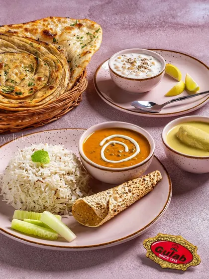 A vegetarian thali featuring dal makhani, kadhi, rice, and lachha paratha, offering a complete and balanced meal.
