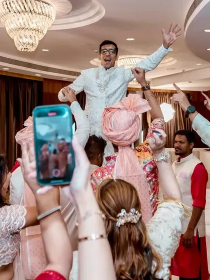 A friend is lifted onto shoulders in the middle of the dance floor, a moment of high energy and celebration, all captured on camera phones.