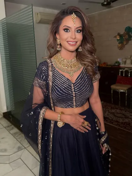 Anushka smiling and glowing in her navy dream outfit. The bold eye makeup gives her an extra touch of drama and confidence for her special event.