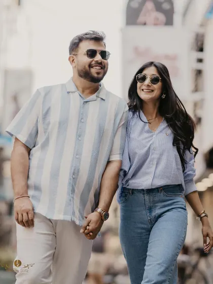 A smiling couple holds hands while walking down a city street. The natural light and their happy expressions make this a perfect example of a relaxed and joyful urban pre-wedding session.