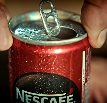 A satisfying close-up of a can of Nescafé being opened. This product shot is a key part of the commercial's visual storytelling.