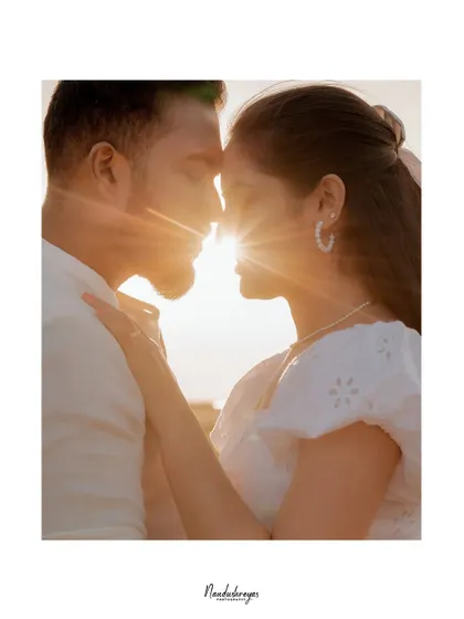 A beautiful silhouette of a couple against a bright sun flare, creating an artistic and romantic portrait.