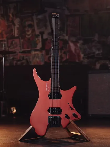 The red Strandberg guitar, showcasing its vibrant color and modern design from a full-frontal angle.