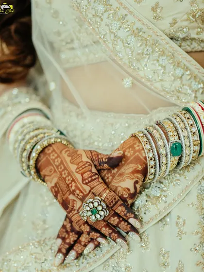 A close-up on the details. This shot highlights the intricate mehendi on the bride's hands, her beautiful bangles, and the stunning engagement ring, capturing the artistry of the bridal look.
