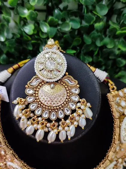 A detailed view of the maang tikka from the classic temple coin necklace set. The piece features delicate pearl work and a traditional design.