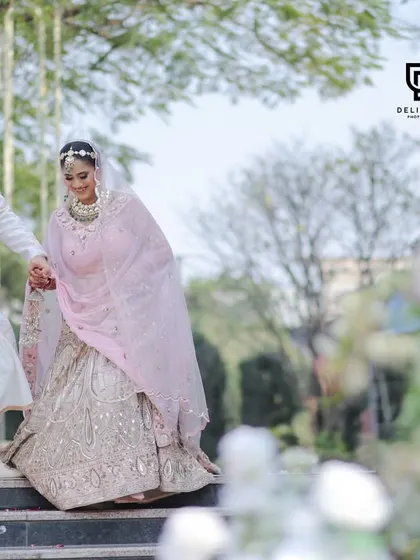 The groom leads his bride down the stairs in a candid, happy moment. The soft floral foreground adds a dreamy, artistic touch to this wedding photograph.