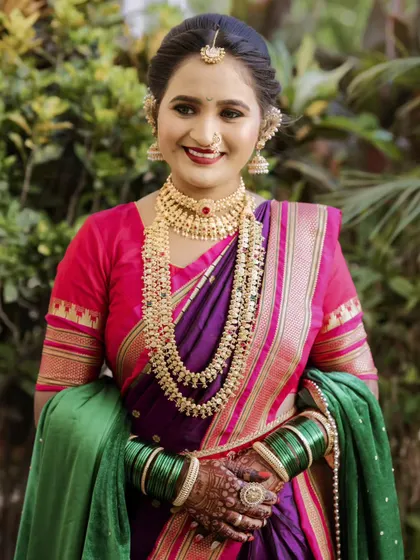 A bright and cheerful portrait of the bride in her purple and green paithani, looking directly at the camera with a warm smile.