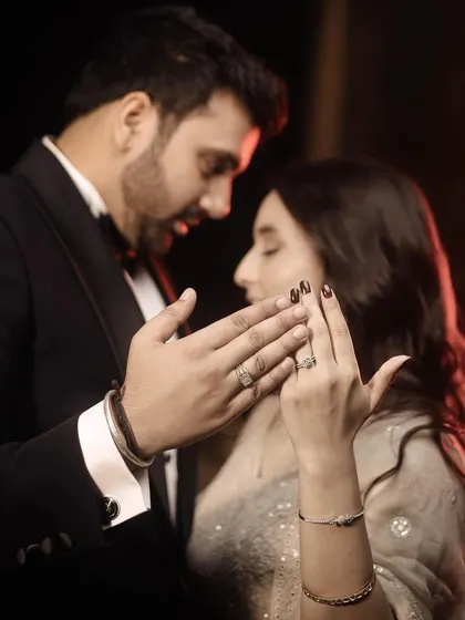 An intimate and artistic engagement photo, focusing on the couple's hands and rings.