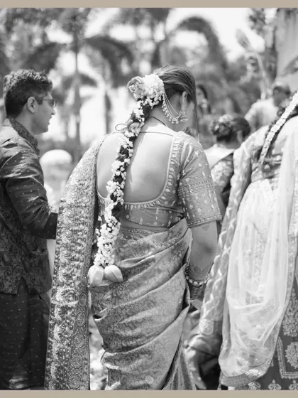 A timeless black and white photo capturing the bride from behind, showcasing her traditional hairstyle adorned with flowers.