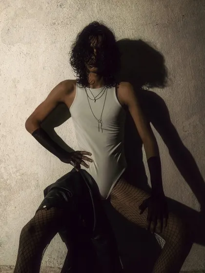 A conceptual shot playing with shadows and form. The model's body creates interesting shapes against the textured wall.