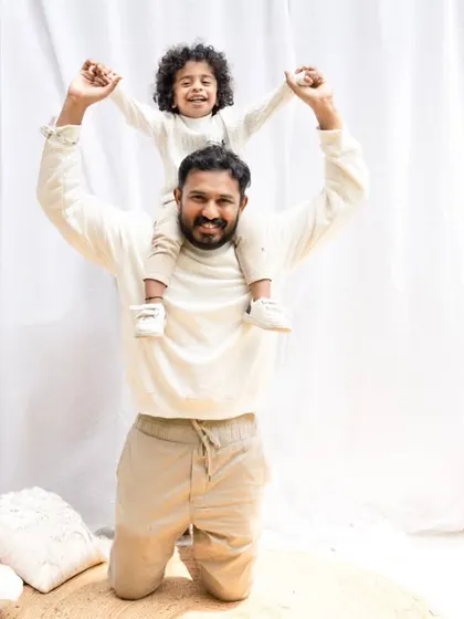 A fun father-son moment with the son on his dad's shoulders, both enjoying the fresh air during their outdoor shoot.