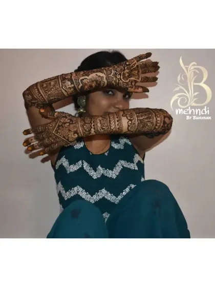 A playful pose showing the intricate arm mehndi that matches the feet design.