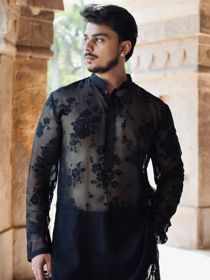 A modern and daring take on ethnic wear. This sheer black kurta features a burnout floral pattern, offering a glimpse of the skin beneath for a bold, high-fashion look.