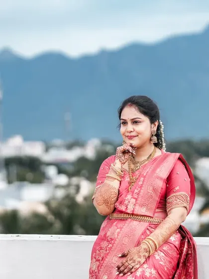 A lovely solo portrait of the bride against the same mountain view, looking radiant in her pink silk saree.