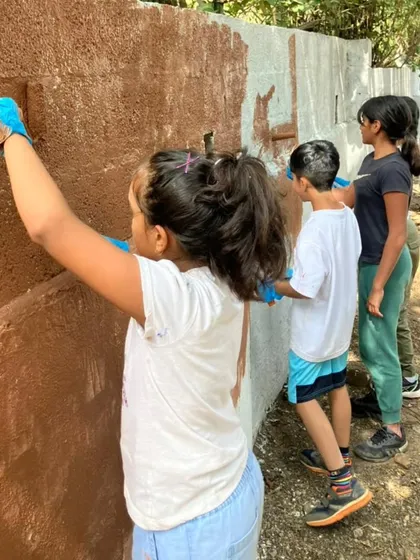 Children work together to paint a wall at the rescue center. This teaches them that conservation is not just about animals, but also about maintaining the spaces that keep them safe.