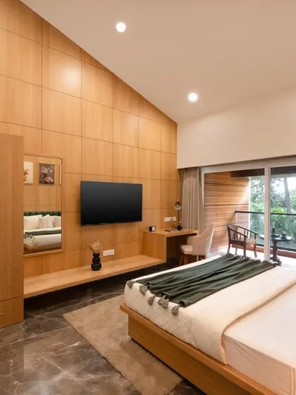 This is a full view of one of the master suites, showcasing the integrated custom furniture. The wardrobe, TV console, and desk are all crafted from the same light wood, creating a cohesive and sophisticated look that maximizes space.