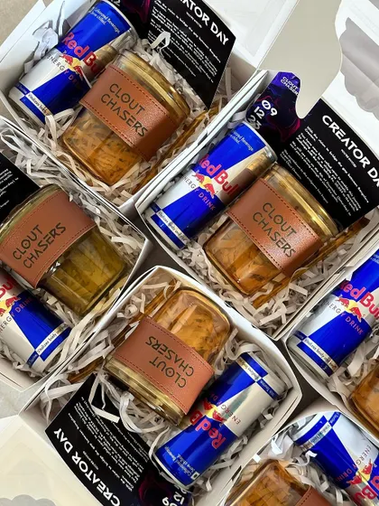 Multiple PR gift boxes for 'Clout Chasers' filled with branded tumblers and Red Bull cans, ready for an influencer event.