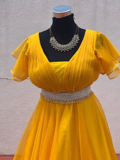 A close-up of the pleated bodice and flutter sleeves on the yellow gown.