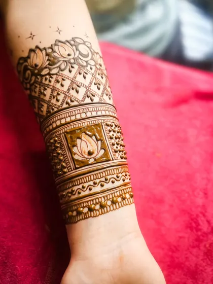A beautiful engagement henna design featuring lotus motifs and delicate latticework on the forearm. This is a perfect example of elegant and modern bridal art.