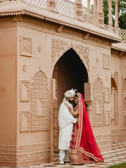 An intimate portrait of the couple framed by an ornate archway. The groom's embrace and their close proximity create a feeling of love and protection.