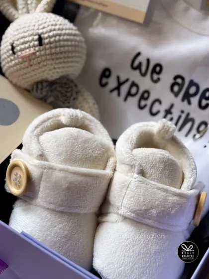 The essentials of a sweet surprise. This hamper combines a "We are expecting" onesie with soft baby booties and a hand-crocheted rattle.