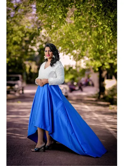 This modern and chic outfit, featuring a navy blue high-low skirt with a long train and a white 3D floral crop top, is perfect for a stylish urban pre-wedding shoot.
