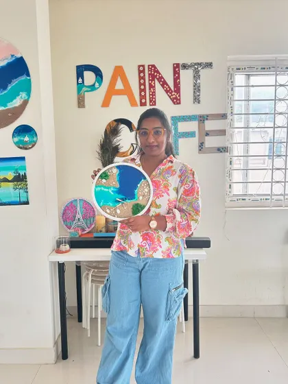 A participant holds her completed beach resin art, showing a different take on the ocean theme.