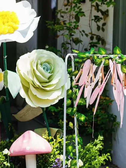 Oversized paper flowers and whimsical mushroom props add a touch of fantasy to the garden theme. These large-scale elements are great for making a big visual impact.