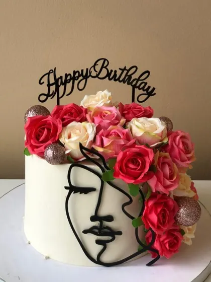 Another view of the artistic cake with a face silhouette and a crown of fresh roses.