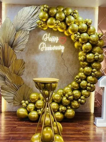 A classic and elegant 1st anniversary celebration. The all-gold balloon ring, accented with dried palm leaves and a neon sign, creates a luxurious and romantic photo spot. The light-up number '1' and custom cake stand complete this beautiful setup.