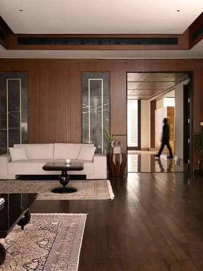 The interior of the Mehalin Farm den, showing the rich wood paneling and its connection to the wider circulation spaces. The design prioritizes an open feel while maintaining distinct functional zones.