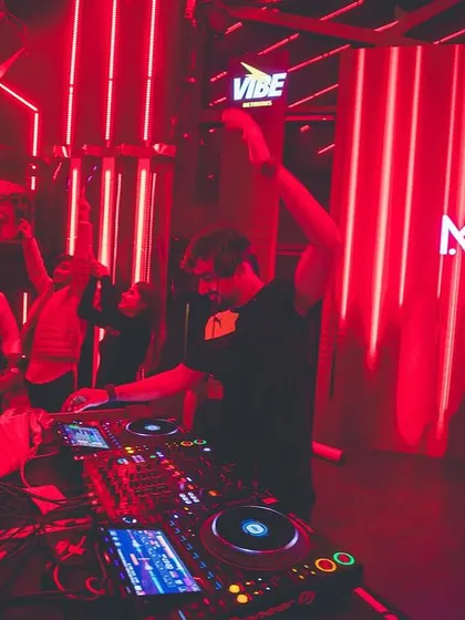 The whole club is bathed in red light as I raise a hand with the crowd. Creating a powerful, unified atmosphere is key to my performance philosophy.