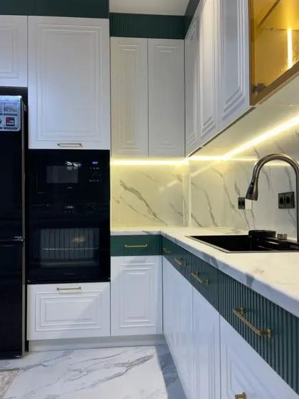 A detailed shot of the green and white classic kitchen, showing the integrated oven and microwave unit and the beautiful fluted panel details on the green cabinets.