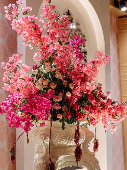 A lush arrangement of pink bougainvillea in a classic white urn. This simple yet beautiful detail adds a touch of natural elegance and vibrant color to the decor.