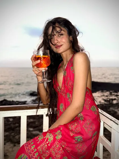 A happy moment with a drink in hand, enjoying the sea view. It's all about finding joy in the simple pleasures of travel.