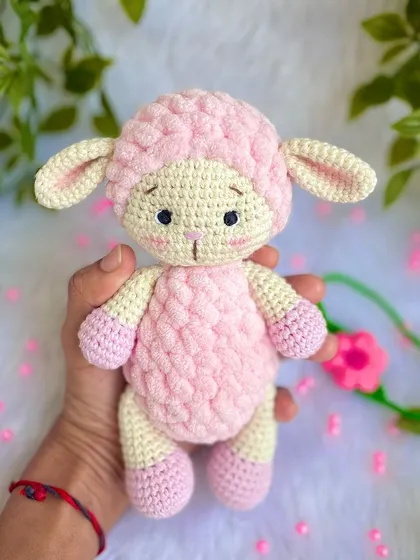 A sweet pink lamb made with a mix of regular and fluffy yarn for a lovely texture. She comes with a removable flower headband.
