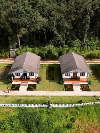 A frontal drone shot of the cottages, showing their neat layout and the beautiful green surroundings.